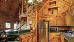 A wooden cabin kitchen with a stainless steel refrigerator, microwave, and stove. - NEW!! Mountain Views! Quiet Escape w/ Fire Pit, Hot Tub, Front Porch Sitting (Sevierville)