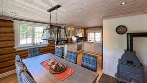 A cozy cabin-style kitchen with a central island, wooden walls, and a wood-burning stove. - Gorgeous home in øyer with sauna (Øyer)