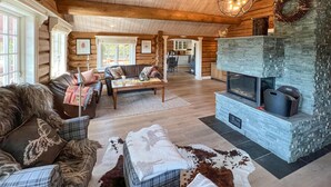 A log cabin interior with a stone fireplace, wooden floors, and a cozy seating area with a sofa and armchairs. - Gorgeous home in øyer with sauna (Øyer)