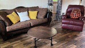 A living room with a brown sofa, a round coffee table, and a red leather chair.