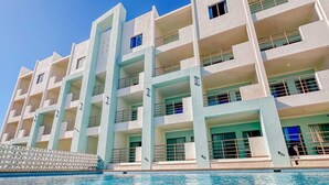 A multi-story hotel with a swimming pool in front.