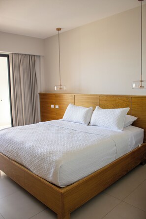 A large bed with a wooden headboard, white bedding, and two pendant lights. - Costa Elegante Hotel & Suites (Puerto Peñasco)