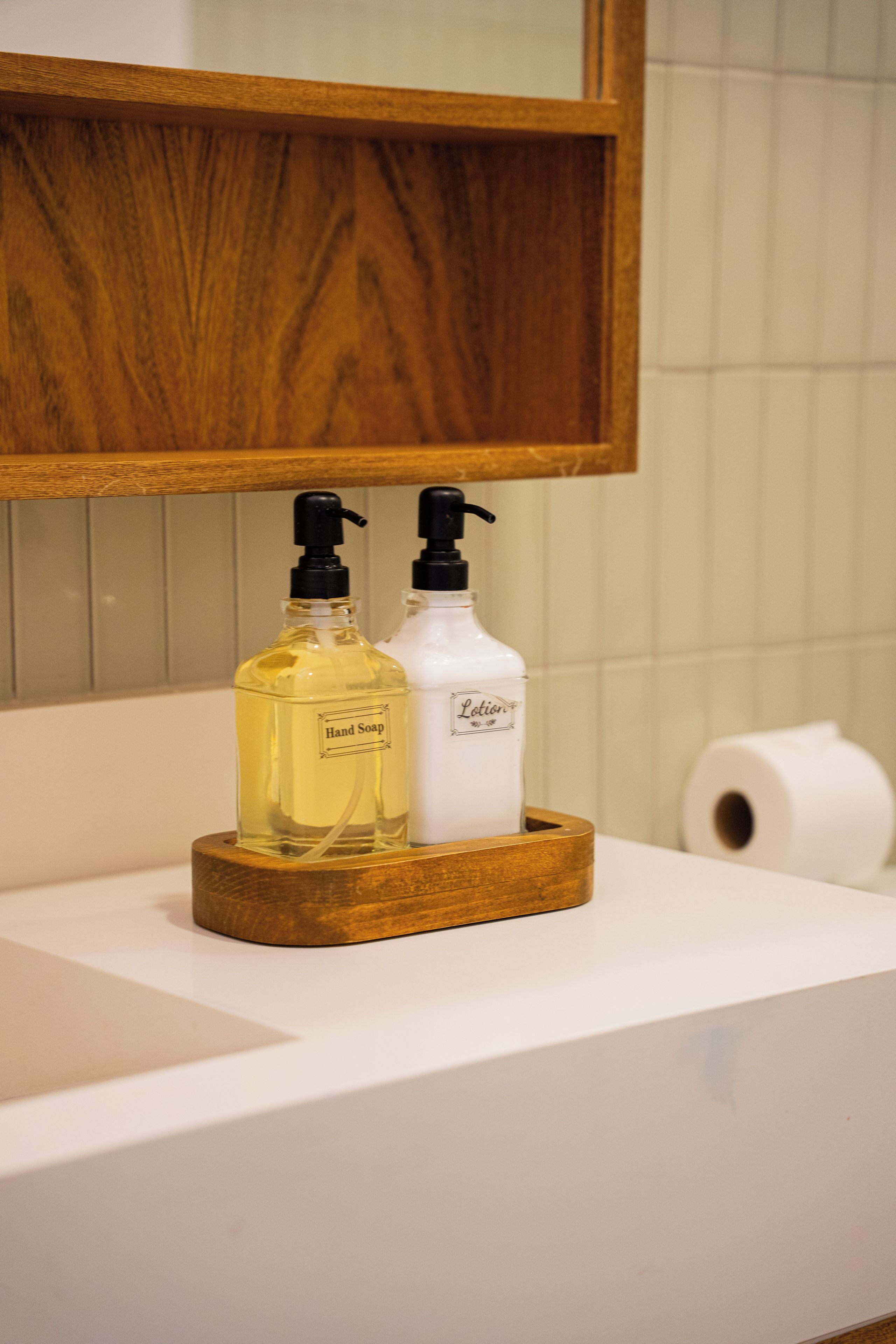 Un lavabo de salle de bain avec deux flacons de savon liquide et un rouleau de papier toilette.