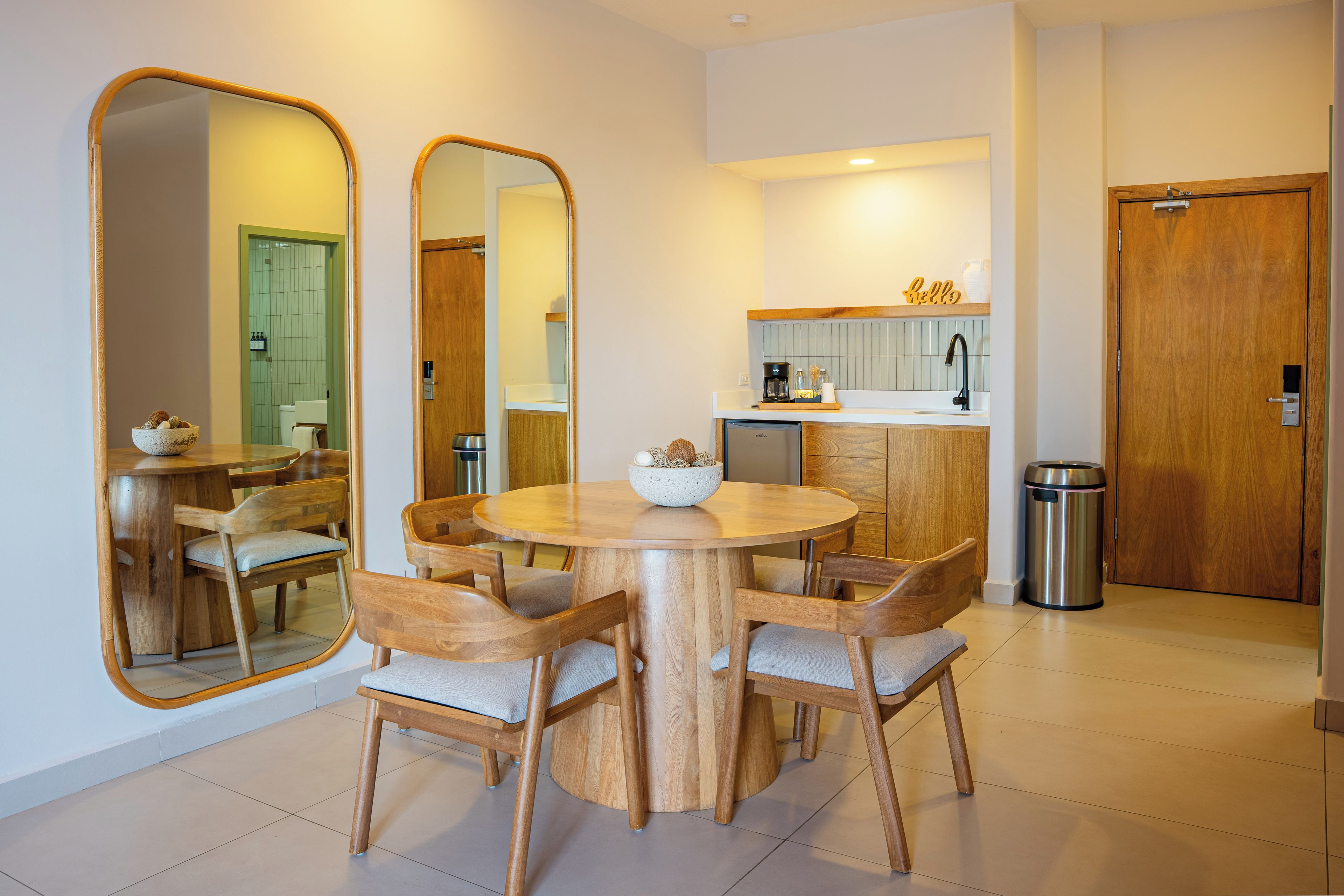 Una cocina moderna con una isla central, sillas de madera, una mesa redonda y un espejo grande.
