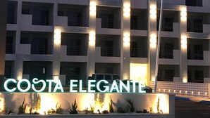 A multi-story building with illuminated signage reading "COSTA ELEGANTE".