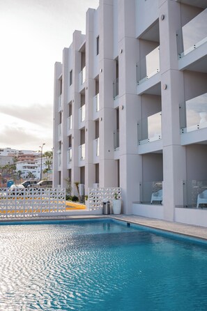 Un edificio moderno con piscina, destacando una fachada geométrica y balcones.