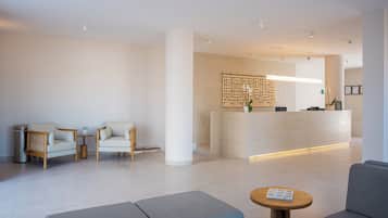 Una moderna zona de recepción con un mostrador, dos sofás, una mesa de centro y un panel decorativo en la pared.