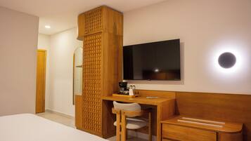 Une chambre d’hôtel comprenant un lit, un bureau avec une chaise, une télévision et une cloison en bois.