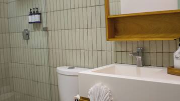 Un baño con inodoro, lavamanos, espejo y toallero.