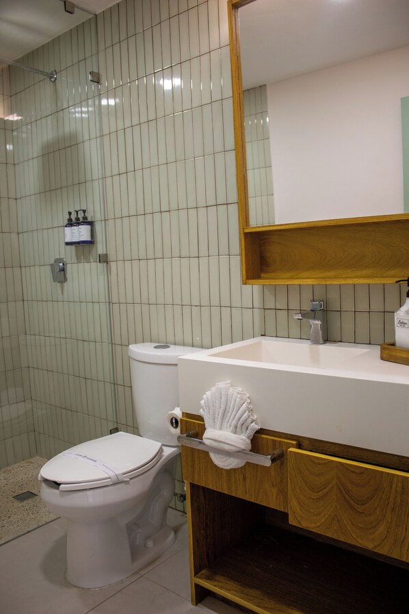 A bathroom with a toilet, sink, mirror, and a towel rack. - Costa Elegante Hotel & Suites (Puerto Peñasco)