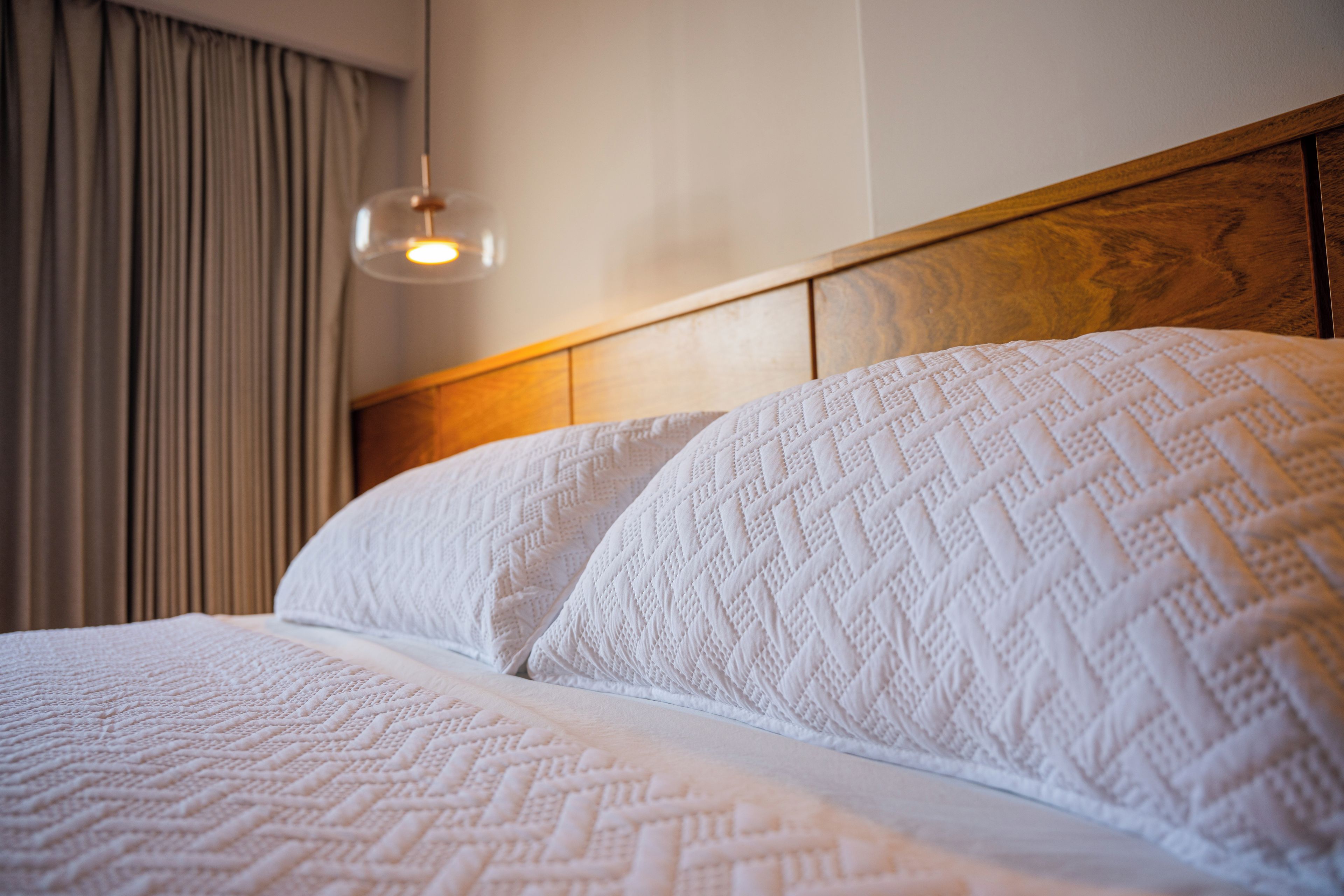 Un letto con biancheria bianca e una testiera in legno.
