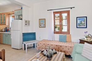 A compact kitchen with a refrigerator, wooden cabinets, and a dining area with a bench and table.