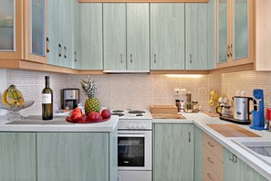 A kitchen with light green cabinets, a stove, oven, and various kitchen appliances.