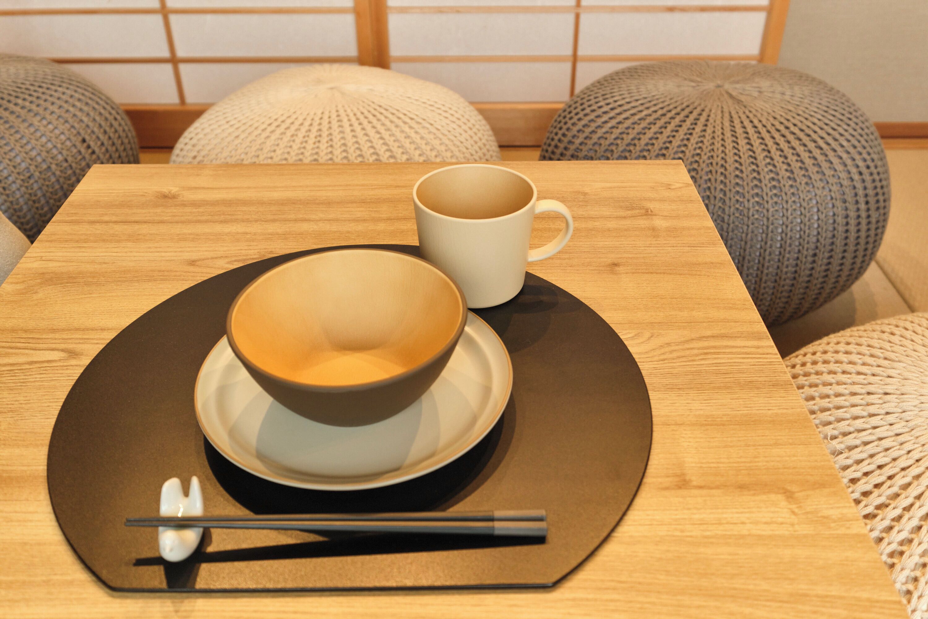 Une table avec un bol et une tasse, des baguettes et une cuillère sur une assiette noire.