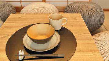 A table with a bowl and a cup, chopsticks, and a spoon on a black plate.