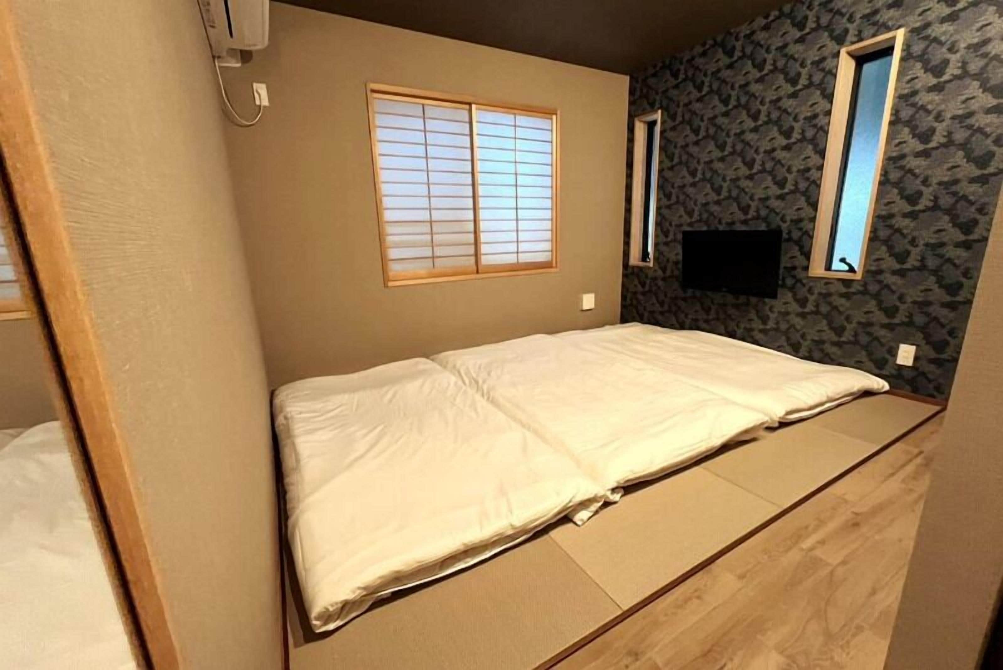 Una habitación con una cama, ventana y televisión en la pared.