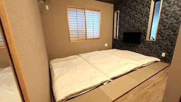 Una habitación con una cama, ventana y televisión en la pared.