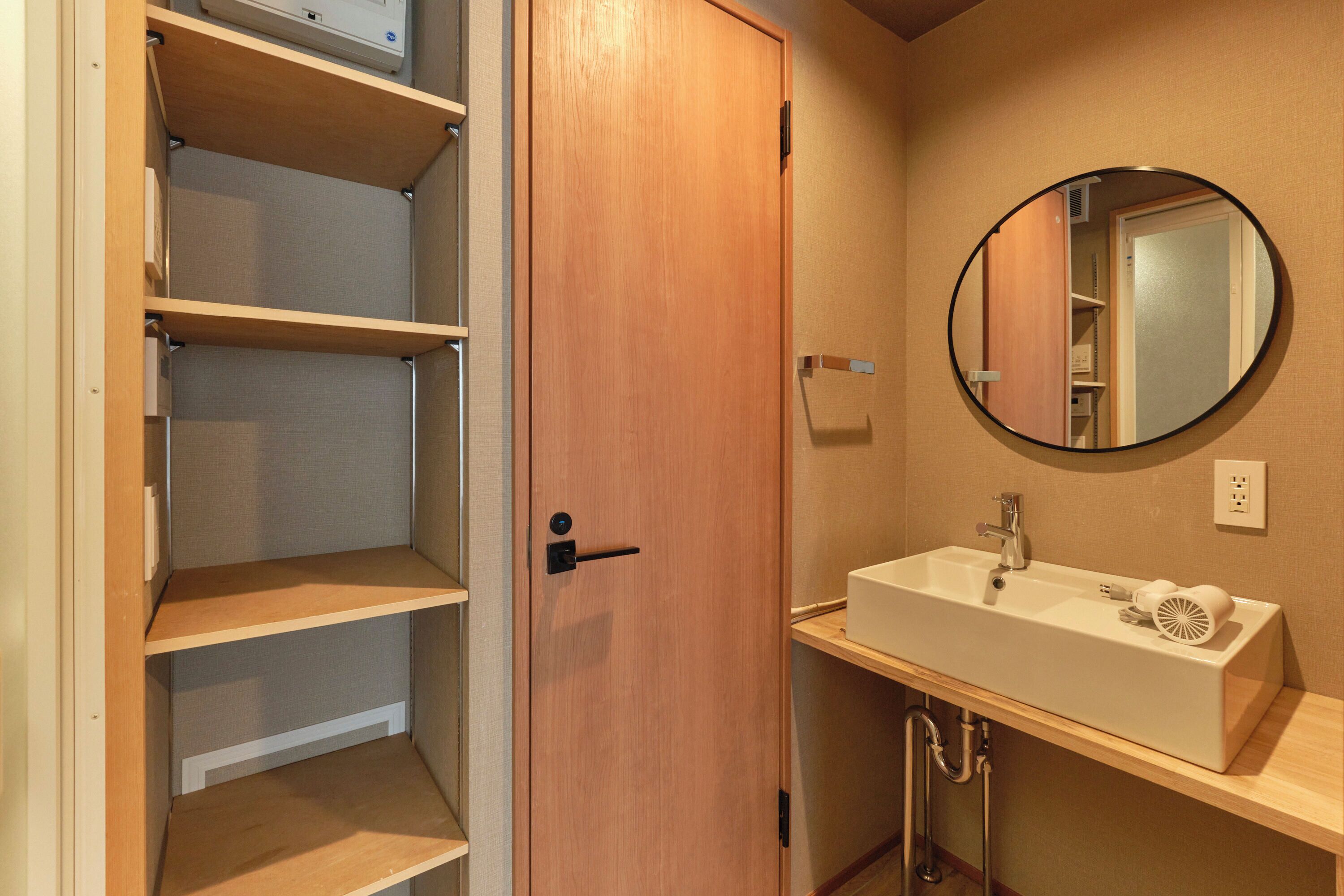 A bathroom with a wooden door, a white sink, a mirror, and a towel rack.