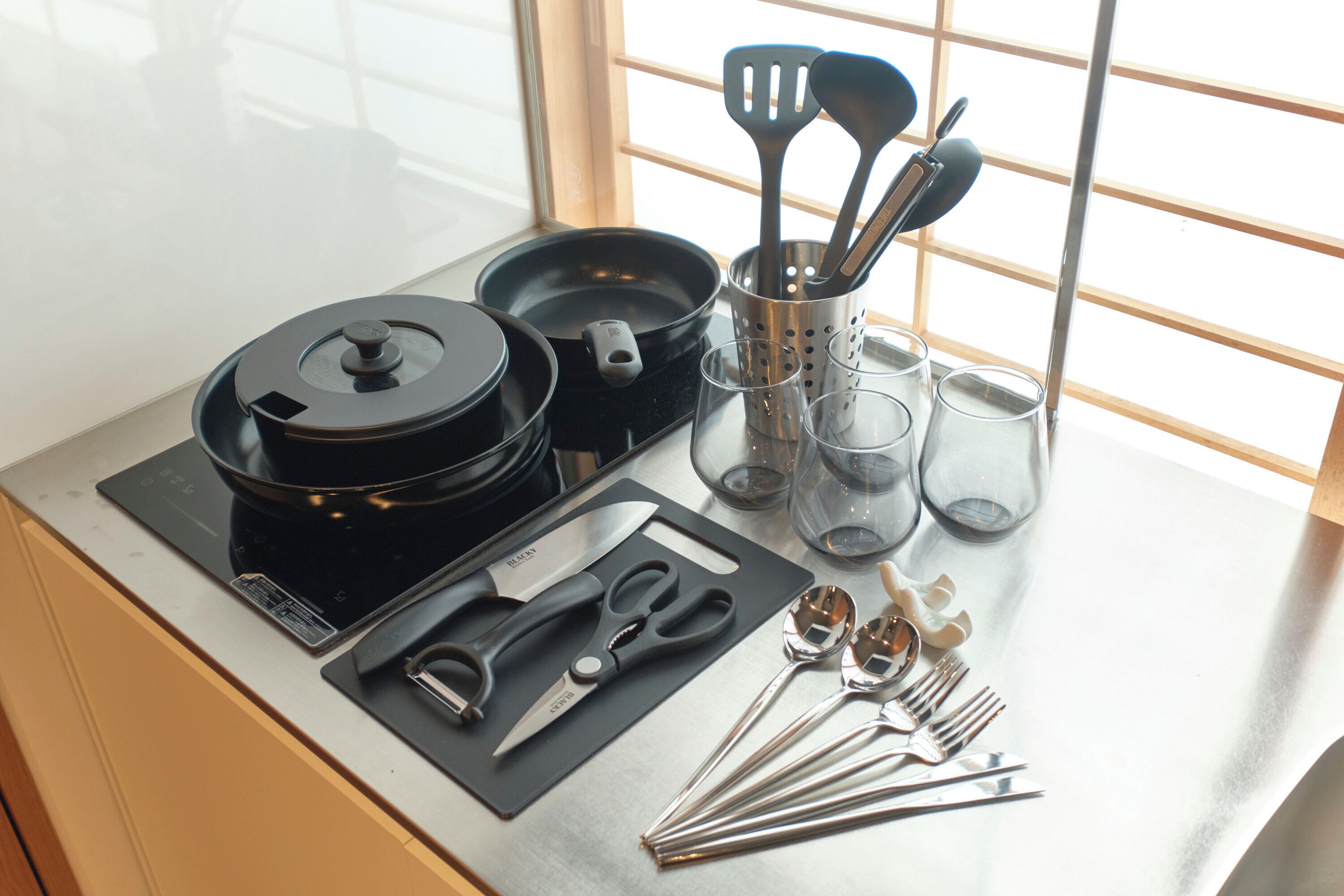 A kitchen counter with a rice cooker, a set of knives, scissors, and various kitchen utensils.