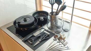 A kitchen counter with a rice cooker, a set of knives, scissors, and various kitchen utensils.