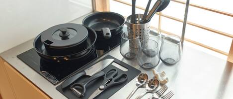 Una encimera de cocina con una cocedora de arroz, un juego de cuchillos, tijeras y varios utensilios de cocina.