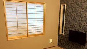 A room with tatami flooring, a shoji screen window, a small window, and a mounted television. - Ryokan Zen Asagaya by Tranova (Tokyo)