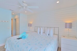 A bedroom with a bed, ceiling fan, bedside lamps, and a nightstand.