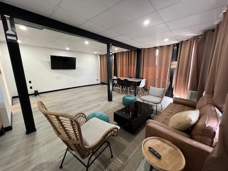 Amplia sala de estar con un sofá, sillas, una mesa de centro y un televisor montado en la pared.