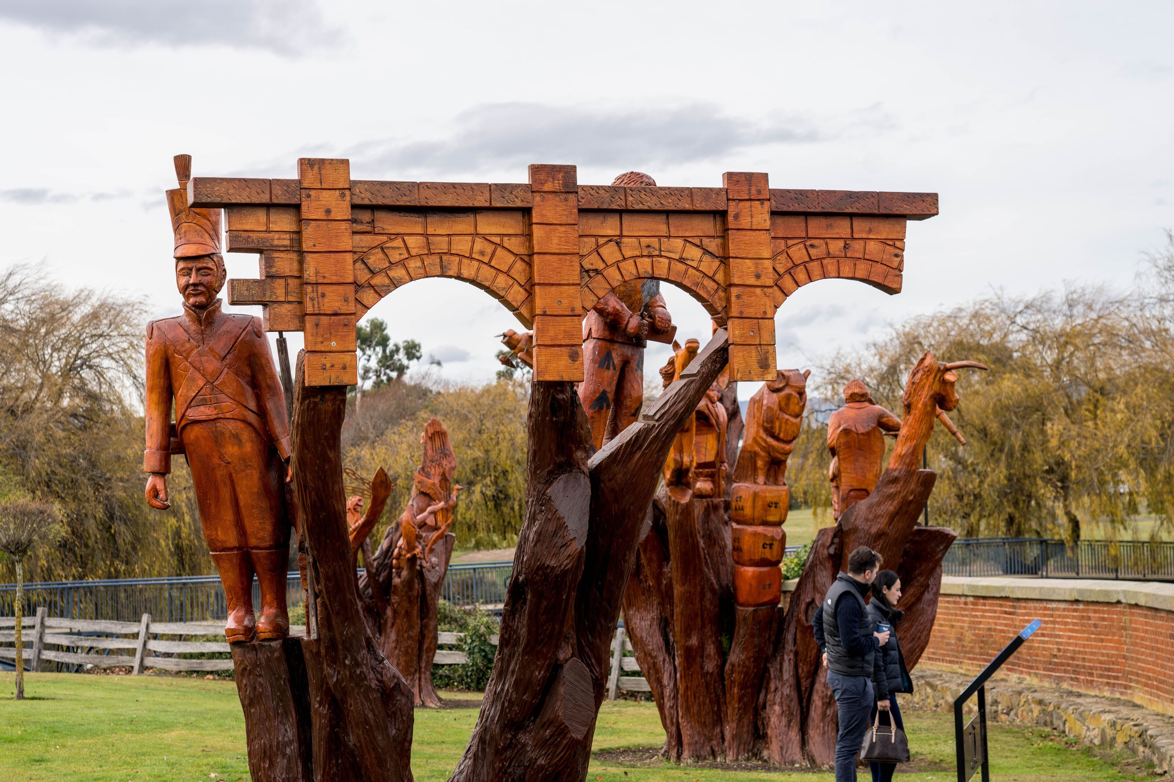 A sculpture of a man in traditional attire standing under a wooden archway.