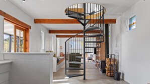 Un intérieur moderne agrémenté d’un escalier en colimaçon, de poutres en bois et d’un coin salon confortable.