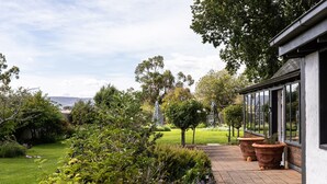 Un chemin de jardin qui mène à un bâtiment doté de grandes fenêtres et d’une façade blanche.