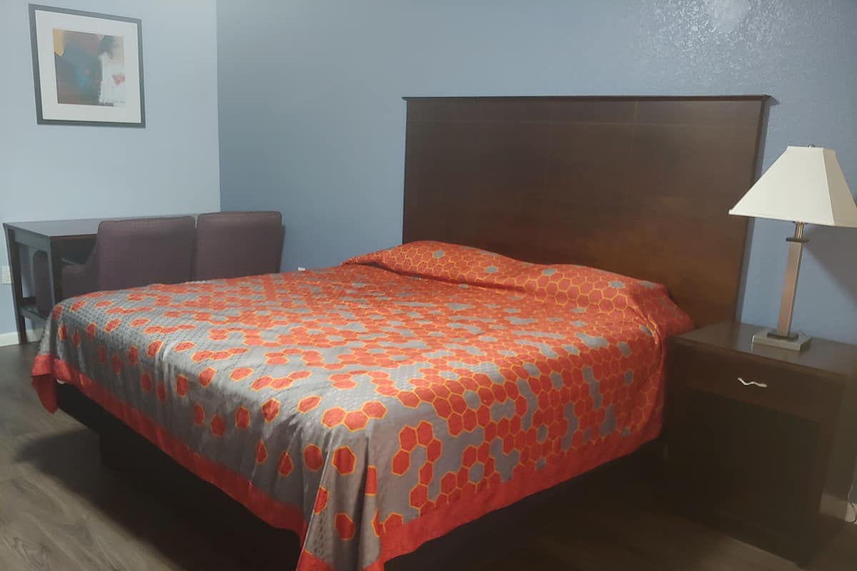 Una habitación de hotel con cama, mesita de noche, escritorio y silla.