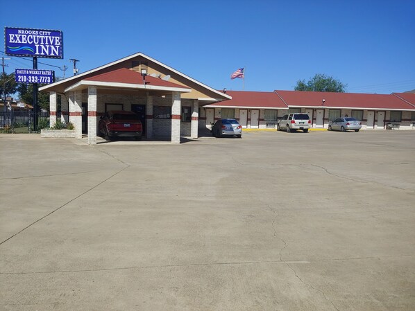 A motel with a red roof, a signboard, and a flag. - Brooks City Executive Inn (San Antonio)