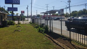 A fenced parking area with a sign for Brooks City Executive Inn, a gas station, and a Quick Stop convenience store. - Brooks City Executive Inn (San Antonio)
