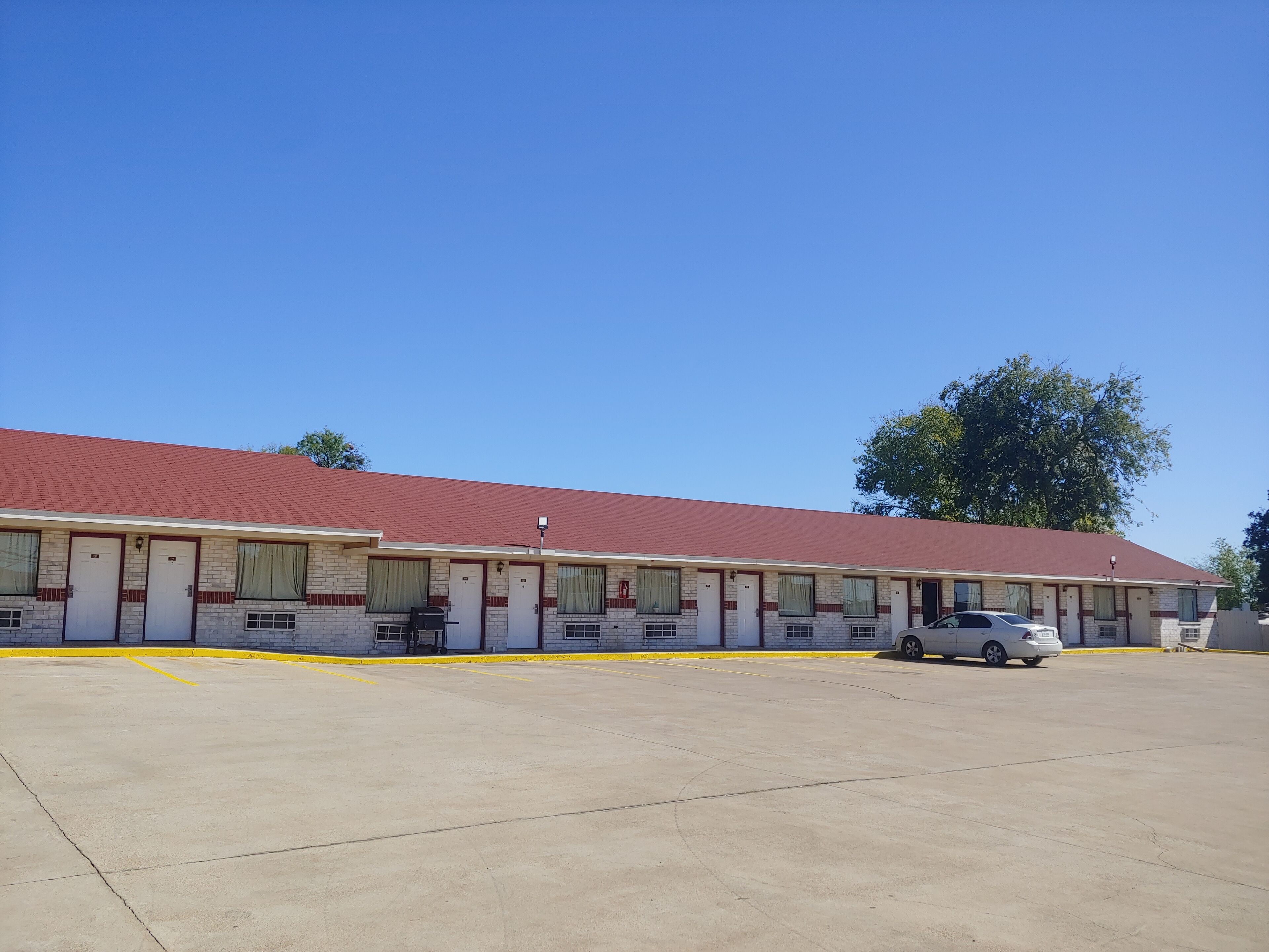 A motel with a red roof and multiple rooms.
