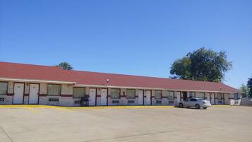 A motel with a red roof and multiple rooms.