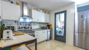 A compact kitchen with white cabinets, a stainless steel range hood, a microwave, and a dishwasher.