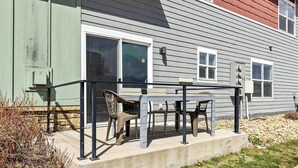 A patio with a table and chairs, a sliding glass door, and a small outdoor area with a stone border. - Cozy townhome in old town north dogs, Bikes. (Fort Collins)