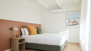 Una camera da letto con un letto, un comodino, una lampada e un quadro appeso al muro.