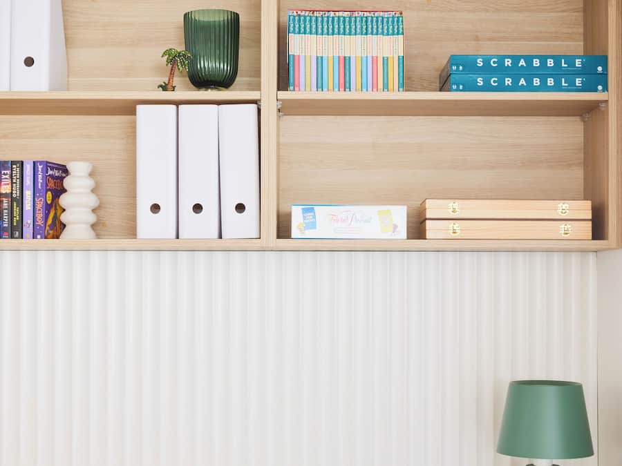 Un espacio de trabajo ordenado con escritorio, estanterías y una lámpara.