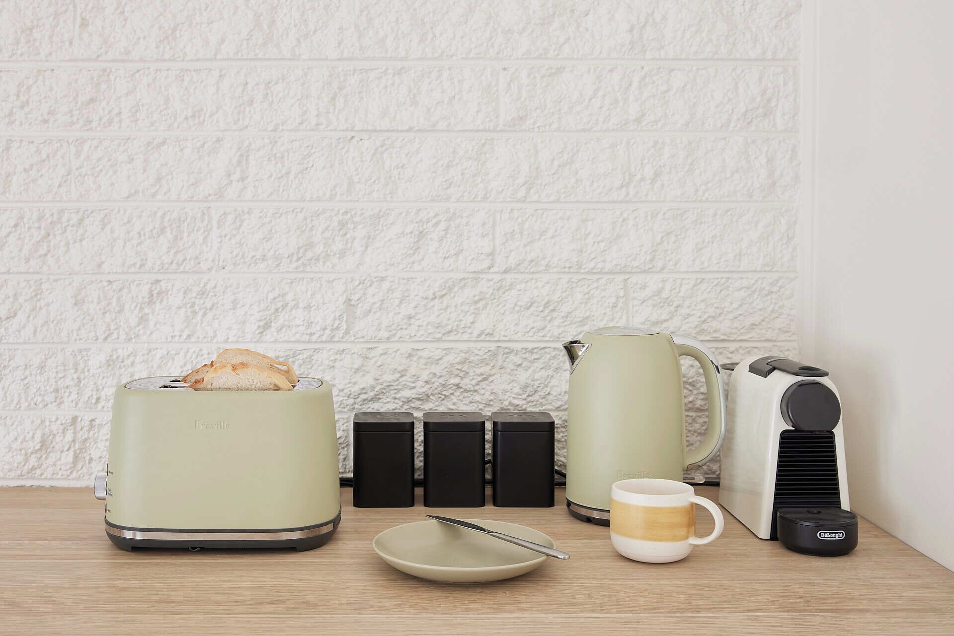 Uma cozinha equipada com torradeira, chaleira, cafeteira, caneca e prato.