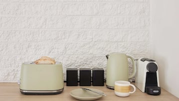 Uma cozinha equipada com torradeira, chaleira, cafeteira, caneca e prato.