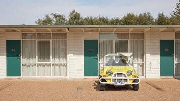 Classic motel with rooms featuring green doors and white-framed windows.