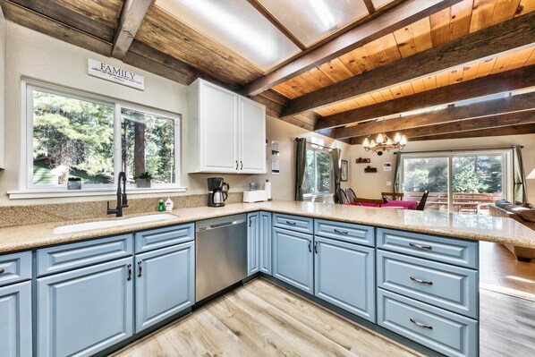 Una cocina con armarios azul claro, encimera de granito y techo de madera.