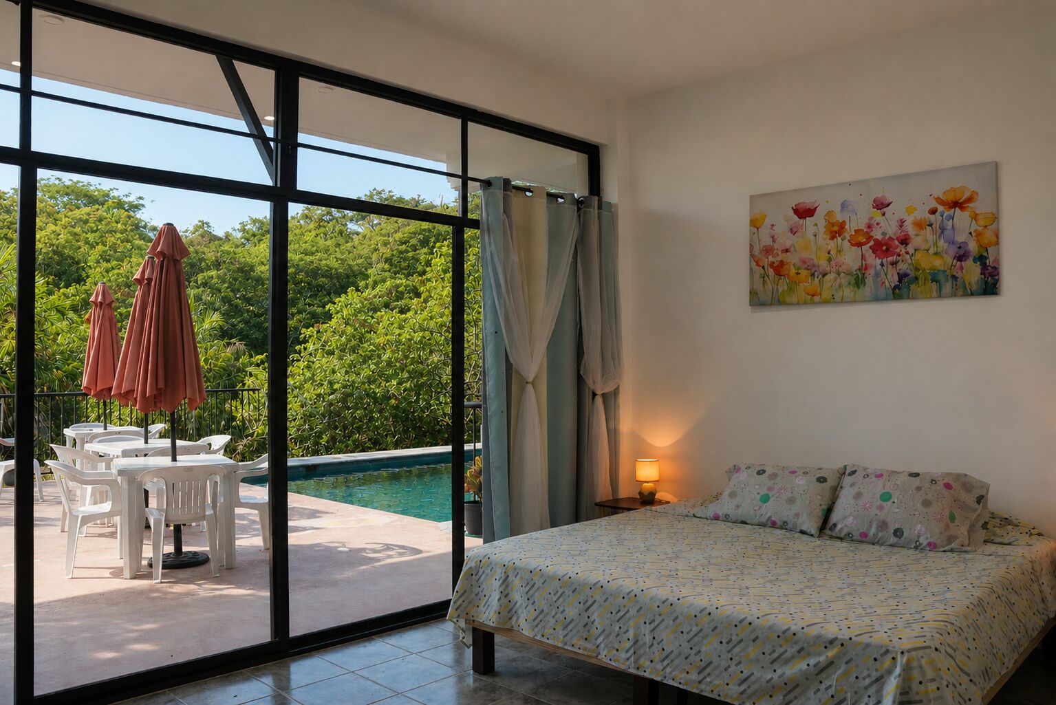 Une chambre à coucher avec un lit, un tableau et une vue sur une piscine et la verdure environnante.