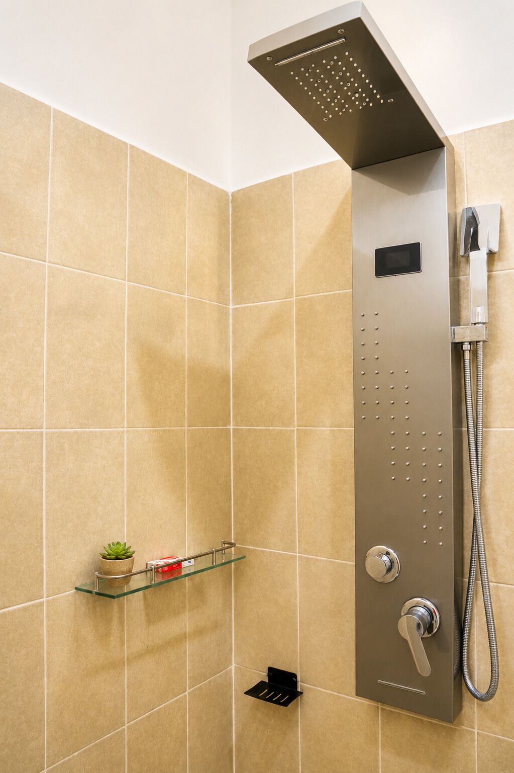 A modern shower with a handheld showerhead and a wall-mounted control panel.