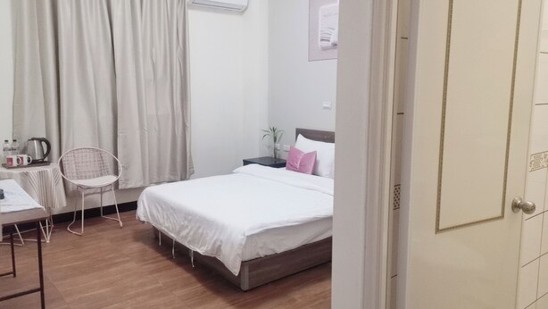 Un dormitorio con cama, escritorio con silla, mesita de noche y ventana con cortinas.