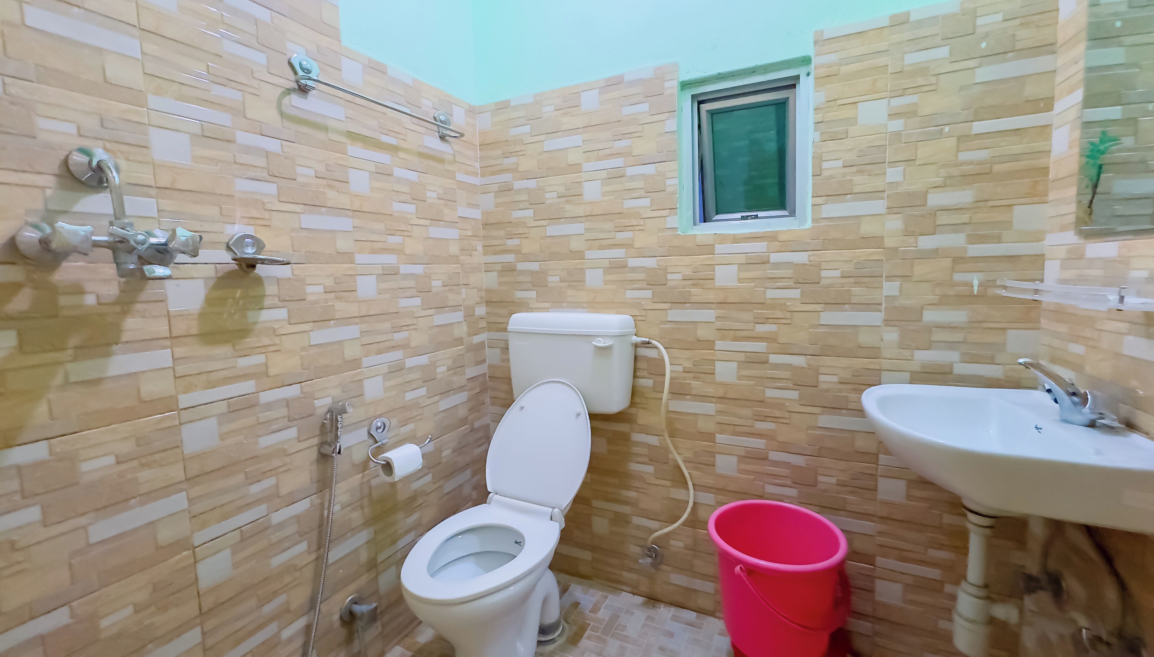Une salle de bain avec des toilettes, un lavabo et une fenêtre.