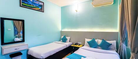 A hotel room with two single beds, a desk with a chair, a mirror, an air conditioning unit, and a ceiling fan.