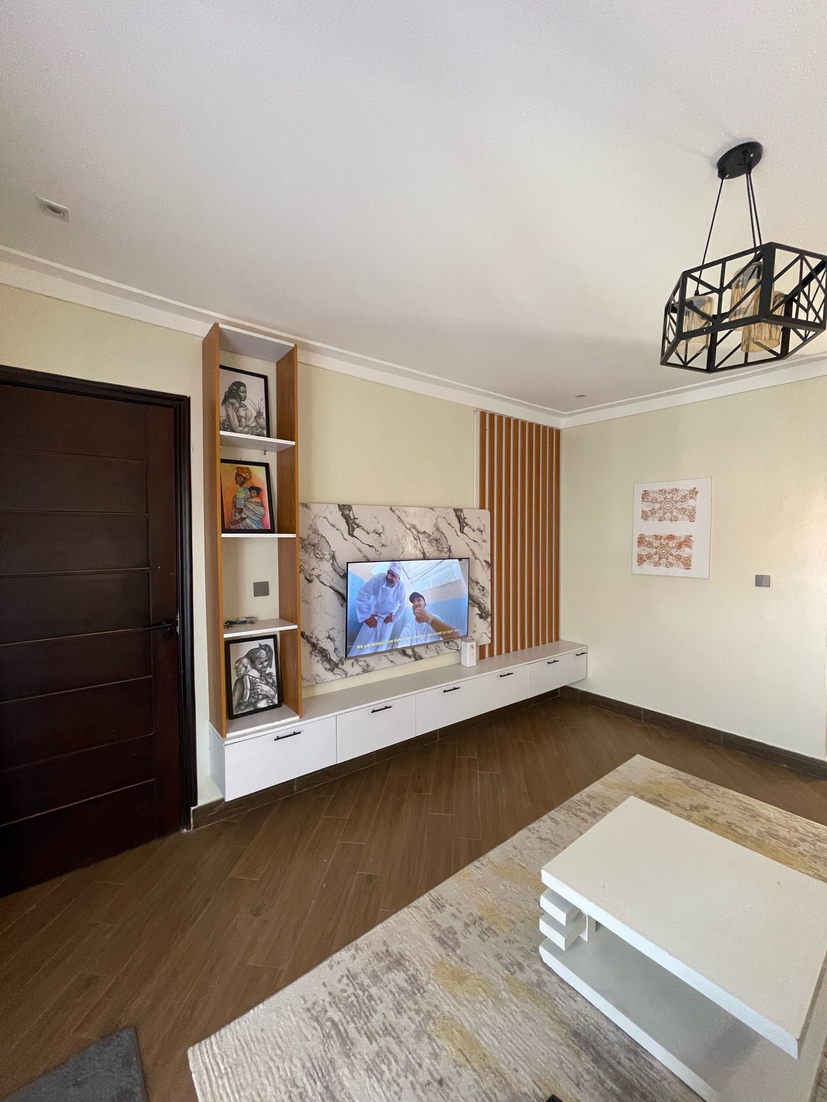 A living room with a TV, wooden panel wall, and a dark door.
